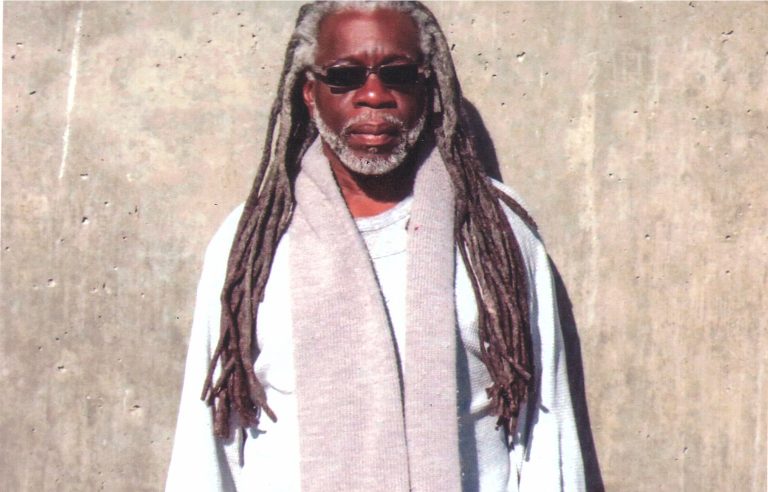 photograph of Dr. Mutulu Shakur in the sun against a concrete wall