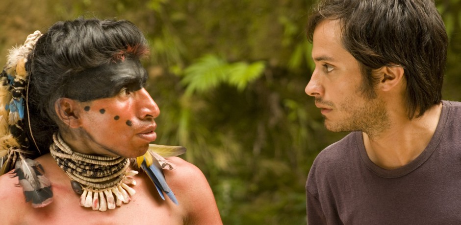two men stare at each other. One man is in costume as an indigenous Taino man in the time of Columbus while the other wears a t-shirt.