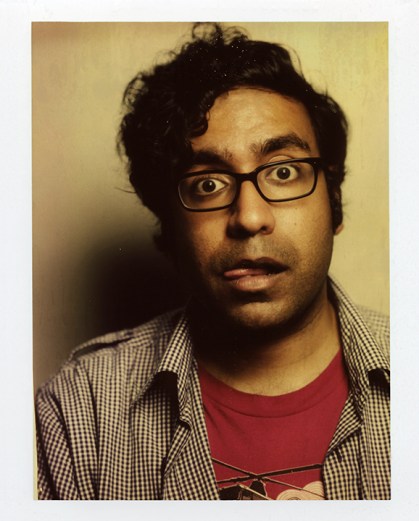Picture of Hari Kondabolu head and shoulders with his tongue sticking out, eyes wide open to the camera